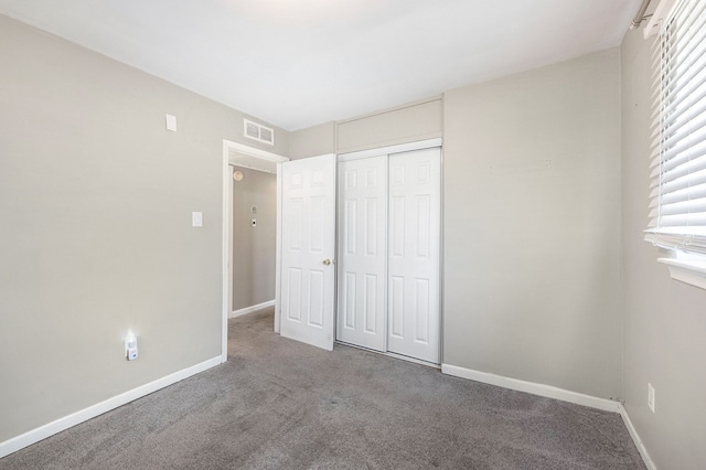 unfurnished bedroom featuring baseboards, visible vents, multiple windows, and carpet