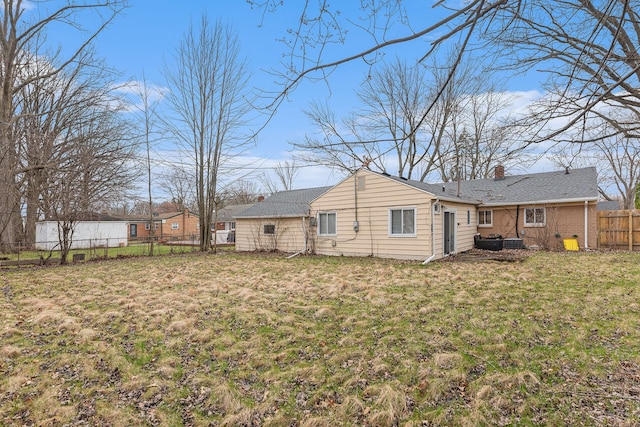rear view of property with a fenced backyard, a lawn, and a chimney