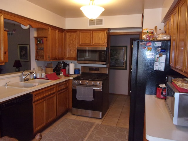 kitchen featuring light countertops, visible vents, a sink, black appliances, and brown cabinetry