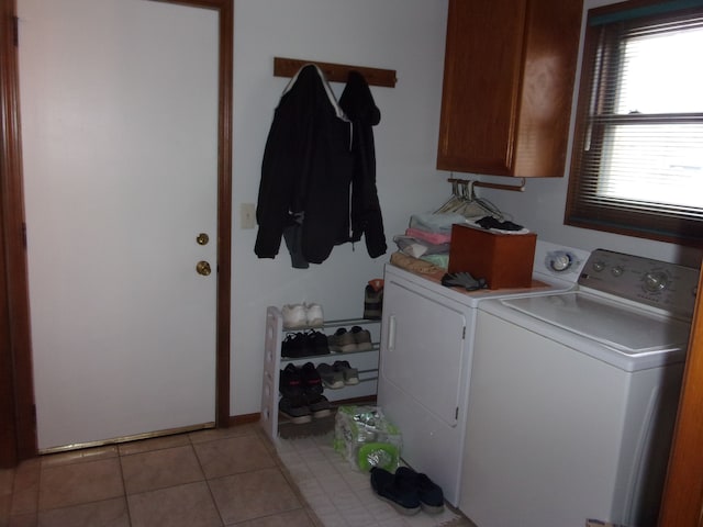 laundry room featuring washing machine and clothes dryer, cabinet space, and light tile patterned floors