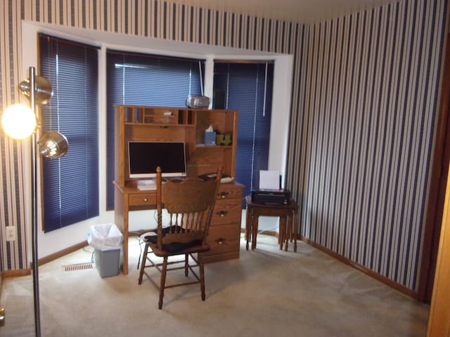 carpeted home office featuring wallpapered walls and baseboards