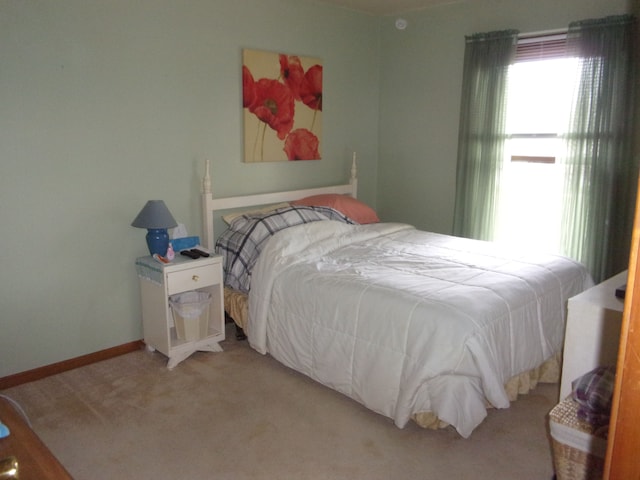 bedroom with light colored carpet and baseboards