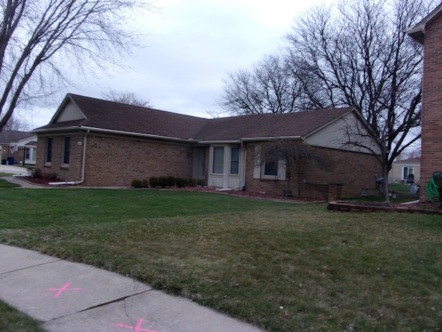 view of front facade featuring brick siding, a shingled roof, and a front lawn