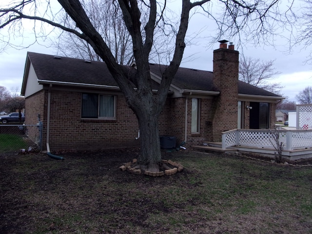 back of property with brick siding, fence, roof with shingles, and a chimney