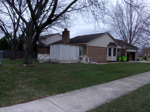 view of front of property with entry steps, an attached garage, a chimney, brick siding, and a front lawn