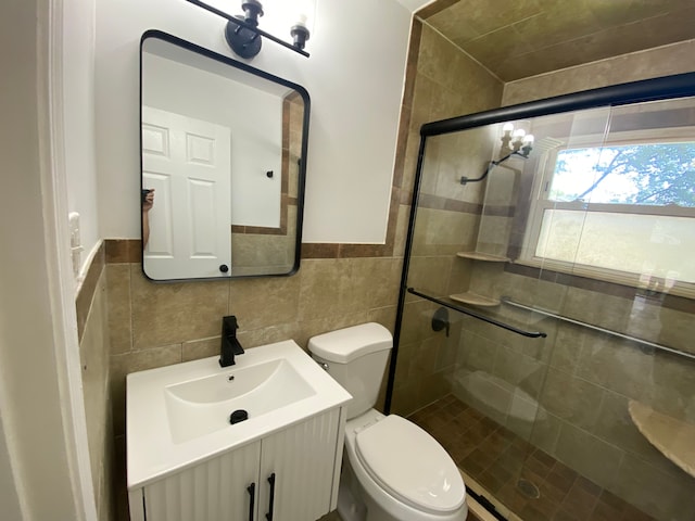 bathroom featuring tile walls, toilet, a stall shower, and vanity