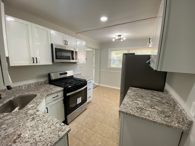 kitchen with light tile patterned flooring, white cabinets, stainless steel appliances, a sink, and light stone counters