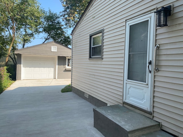 entrance to property with driveway and a detached garage