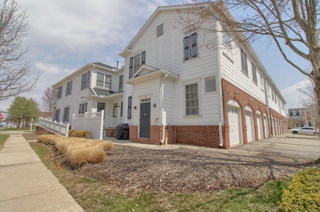 view of front of house with driveway, fence, brick siding, and a garage