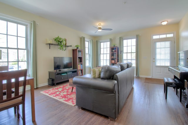 living area featuring a ceiling fan, wood finished floors, and baseboards