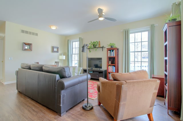 living room featuring wood finished floors, visible vents, and a ceiling fan
