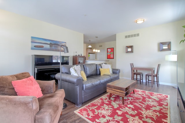 living area with baseboards, visible vents, and wood finished floors
