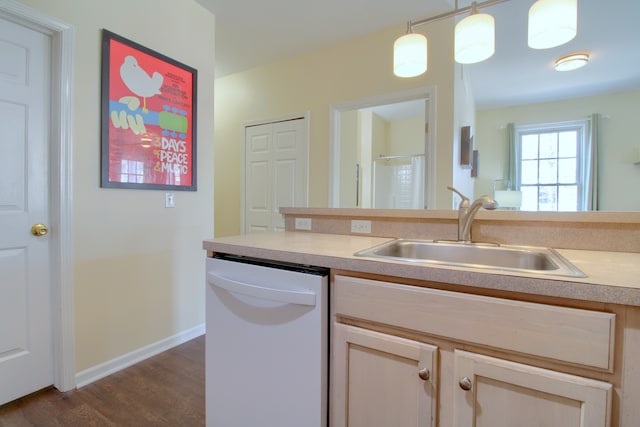 kitchen with a sink, light countertops, dishwasher, and dark wood finished floors