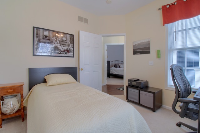 bedroom with baseboards, visible vents, and light colored carpet