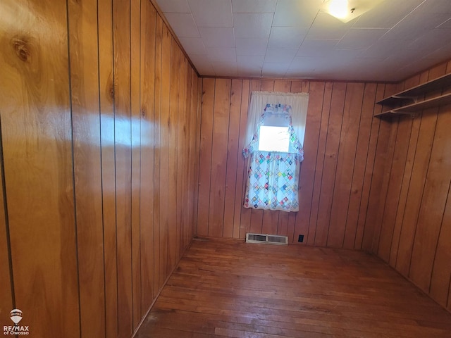 spare room with visible vents, wooden walls, and hardwood / wood-style flooring