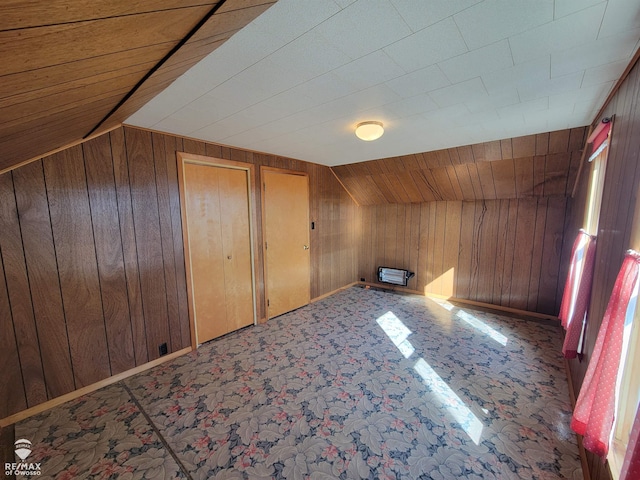 bonus room featuring baseboards, vaulted ceiling, and wood walls