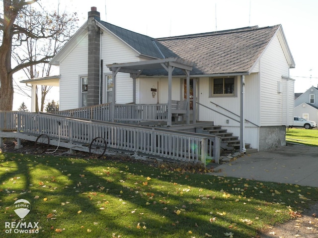 view of front of property featuring a shingled roof, a front lawn, and a pergola