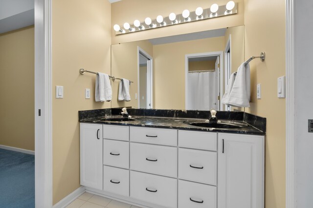 bathroom featuring double vanity, baseboards, a sink, and tile patterned flooring