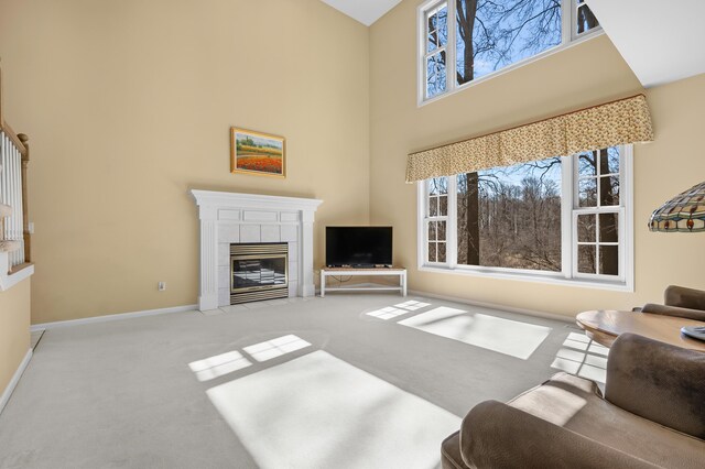 living area featuring a towering ceiling, baseboards, carpet floors, and a tile fireplace