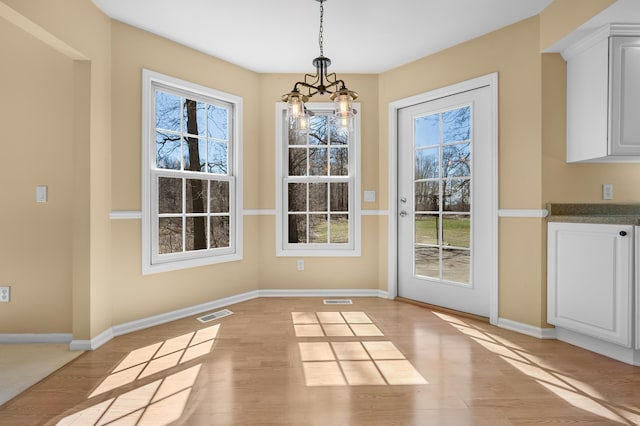 doorway to outside with baseboards, a notable chandelier, and light wood-style flooring