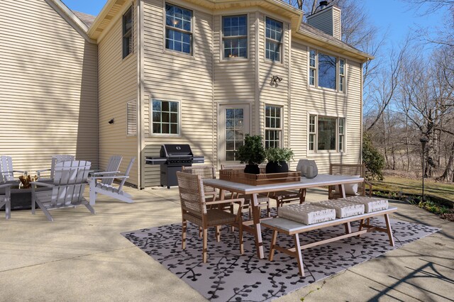 rear view of house with a chimney, outdoor dining area, and a patio area