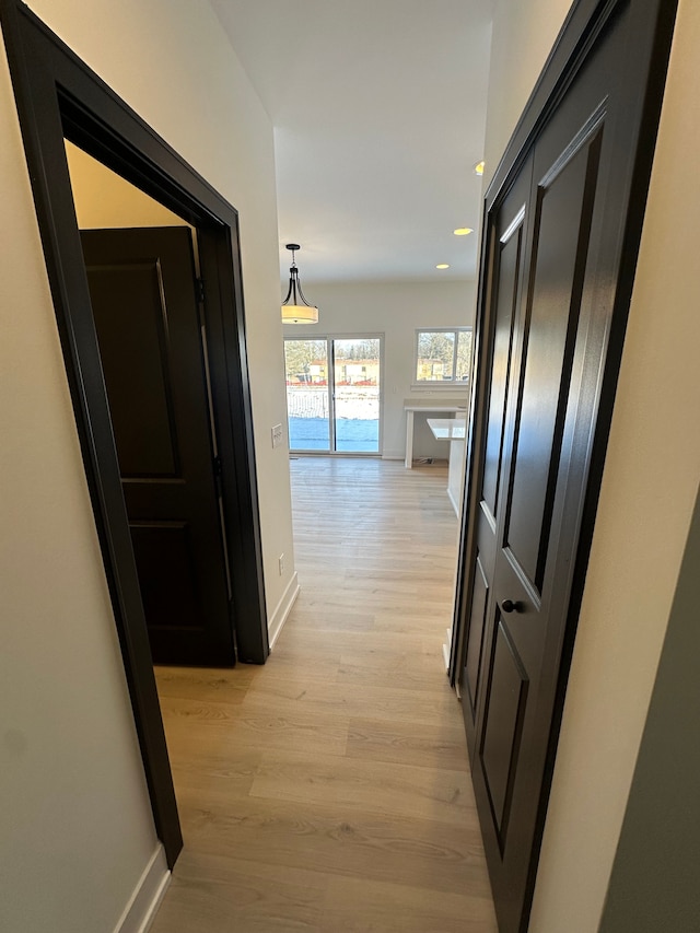 corridor with baseboards, light wood-type flooring, and recessed lighting