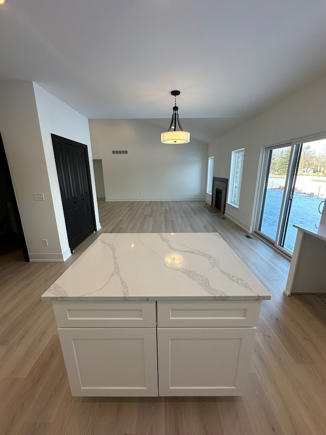 interior space with light wood finished floors, open floor plan, white cabinets, and a fireplace with flush hearth
