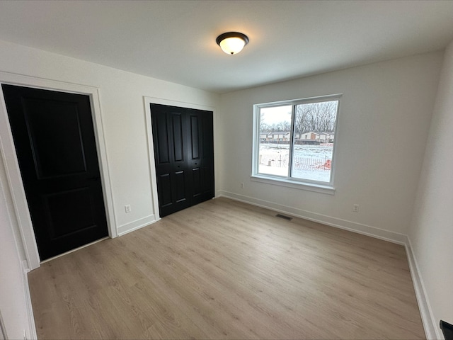 21812 Duns Scotus St # 7, Southfield, MI 48075 - unfurnished bedroom with baseboards, light wood finished floors, and a closet