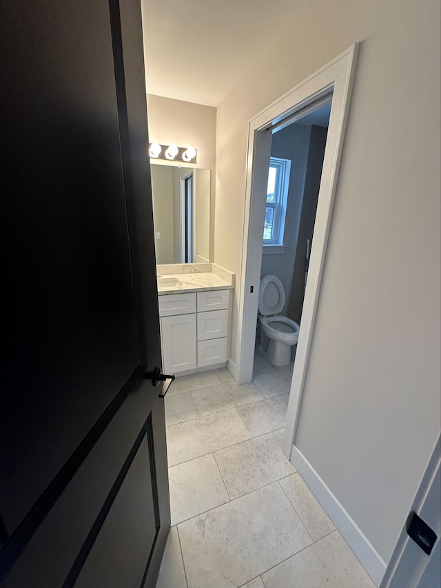 bathroom with baseboards, tile patterned floors, vanity, and toilet