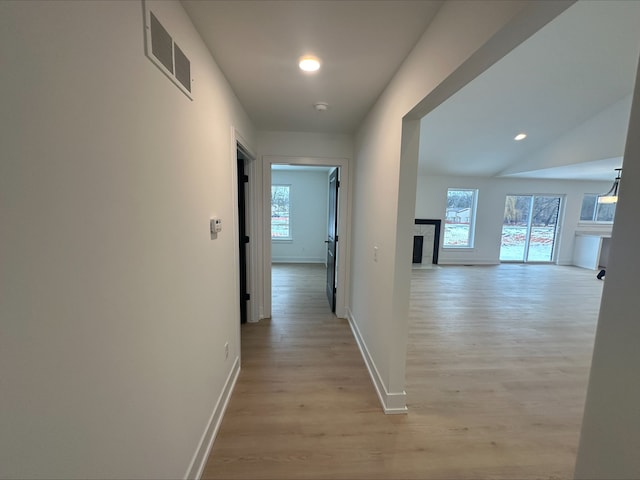hallway with baseboards, visible vents, and light wood-style flooring