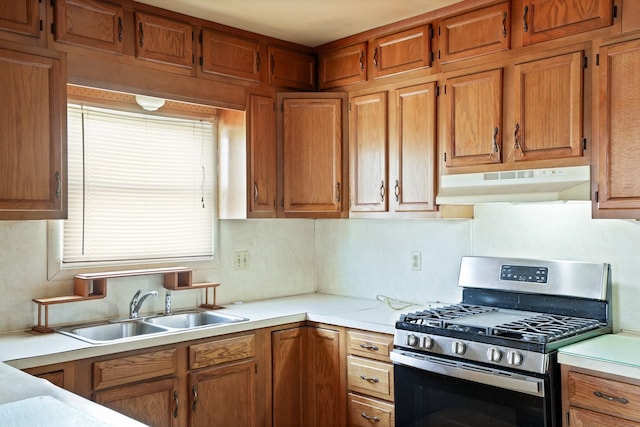 2981 Harrison St, Saginaw, MI 48604 - kitchen with light countertops, stainless steel range with gas stovetop, under cabinet range hood, a sink, and brown cabinets