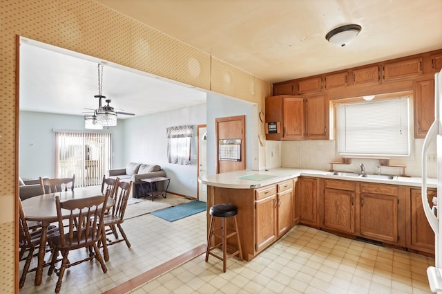 2981 Harrison St, Saginaw, MI 48604 - kitchen with light countertops, a sink, a peninsula, brown cabinets, and open floor plan
