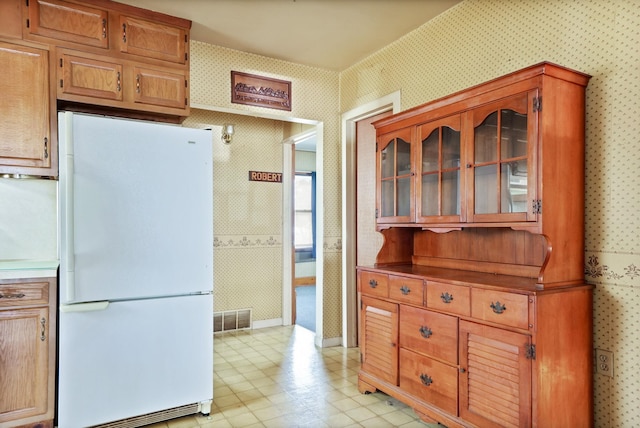 2981 Harrison St, Saginaw, MI 48604 - kitchen featuring freestanding refrigerator, glass insert cabinets, visible vents, baseboards, and wallpapered walls