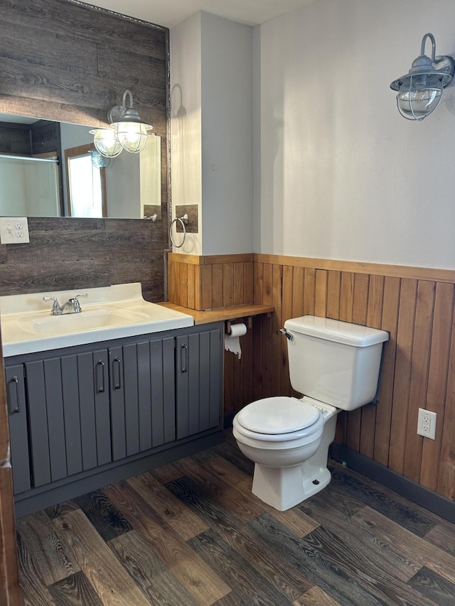 bathroom with wood finished floors, toilet, wainscoting, and wood walls