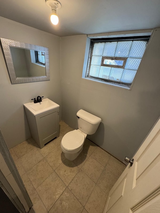 half bath with toilet, vanity, and tile patterned flooring