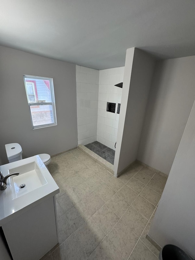 bathroom with toilet, vanity, and tiled shower