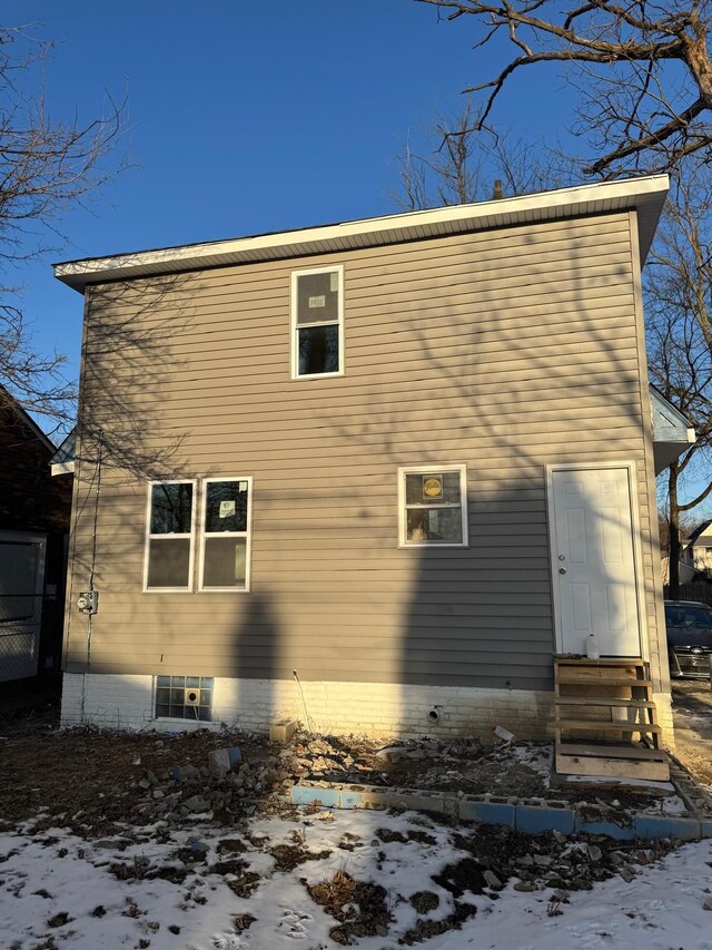 snow covered rear of property featuring entry steps