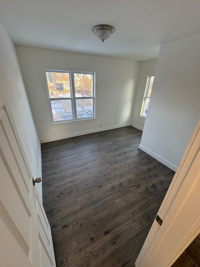 empty room with baseboards and dark wood-style flooring