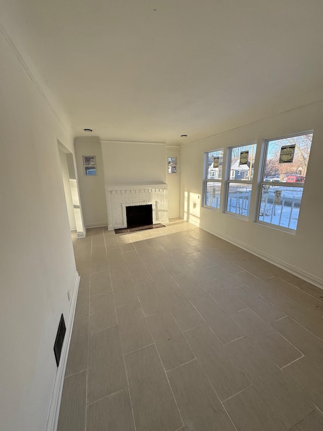 unfurnished living room with a brick fireplace and baseboards