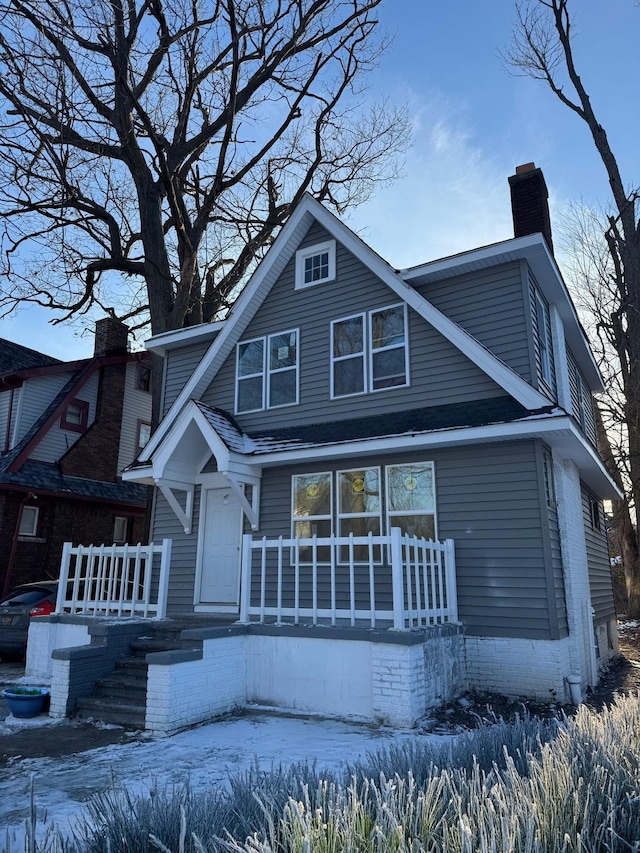 view of front of house featuring a chimney and covered porch