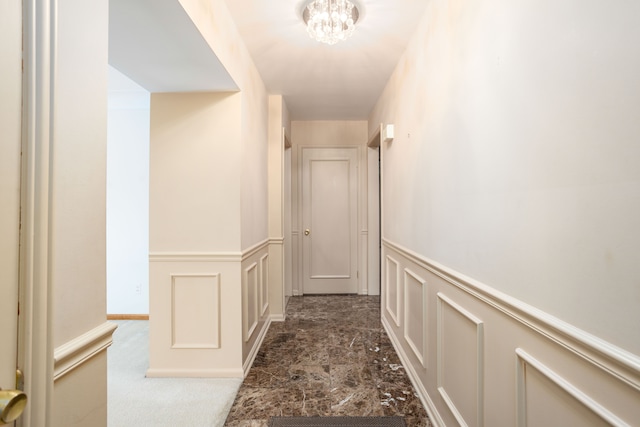 341 Ridgemont Rd, Grosse Pointe Farms, MI 48236 - hall with an inviting chandelier, a decorative wall, and wainscoting