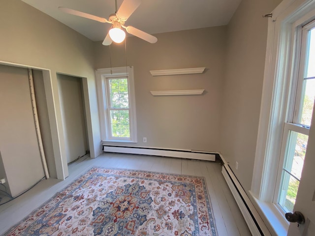 227 Railroad St, Chelsea, MI 48118 - unfurnished bedroom with baseboard heating, a baseboard radiator, ceiling fan, and wood finished floors