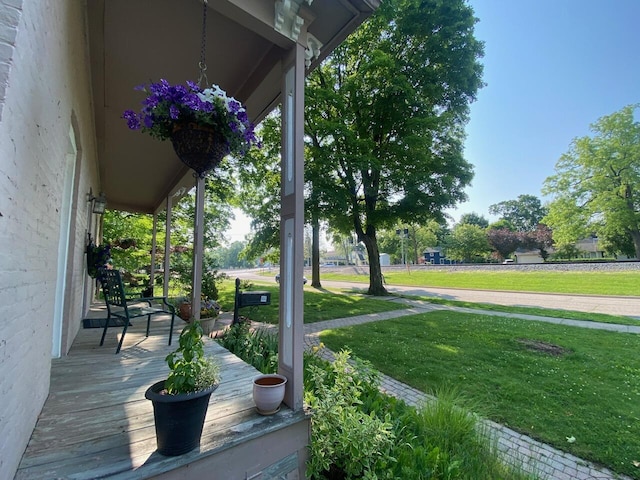 227 Railroad St, Chelsea, MI 48118 - wooden porch featuring a lawn
