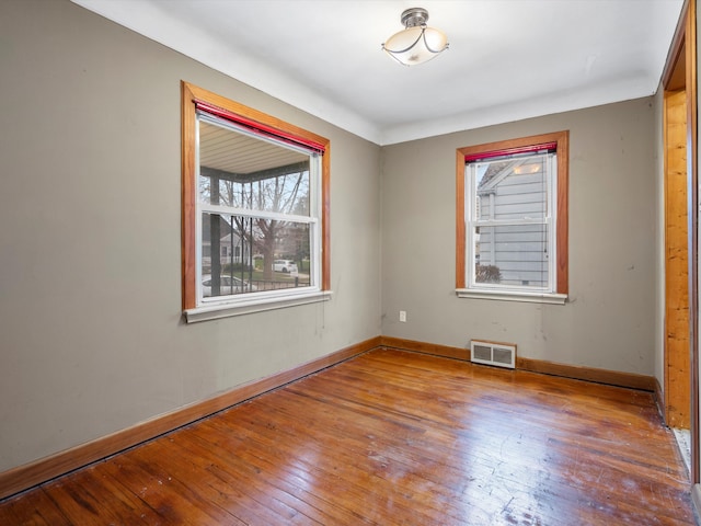unfurnished room with baseboards, visible vents, and hardwood / wood-style flooring