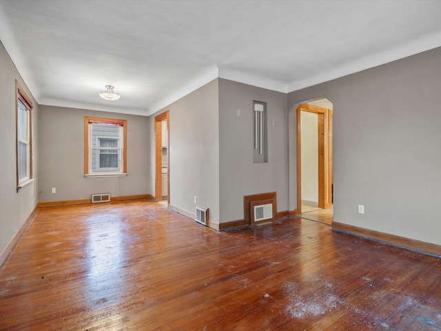 unfurnished room featuring arched walkways, visible vents, and hardwood / wood-style floors