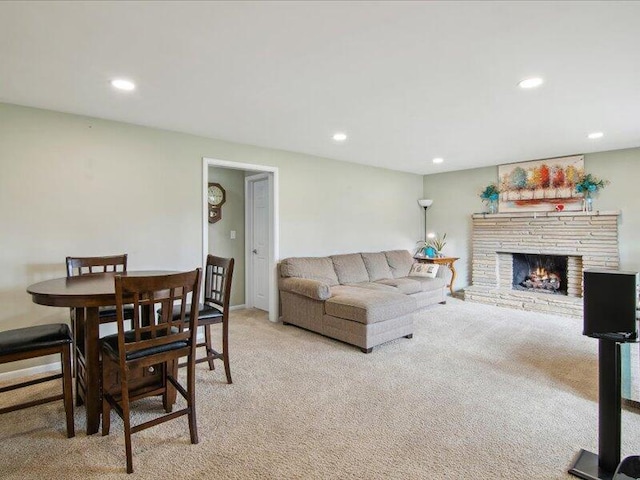 living room with a stone fireplace, recessed lighting, and light colored carpet