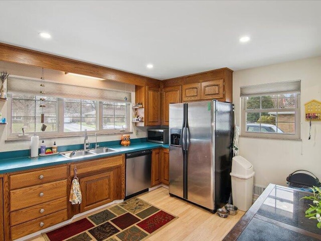 kitchen featuring a wealth of natural light, a sink, brown cabinetry, and appliances with stainless steel finishes