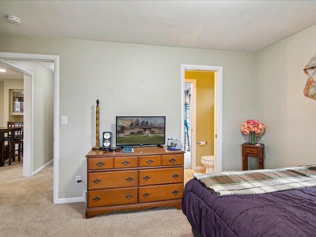 bedroom with connected bathroom, baseboards, and light colored carpet