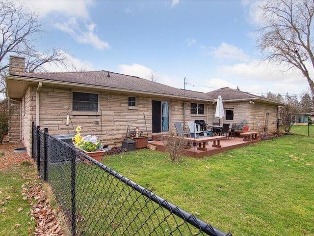 rear view of house with fence, a chimney, stone siding, and a lawn