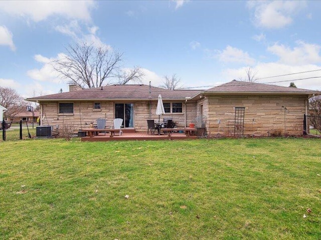 back of house featuring fence, stone siding, and a yard